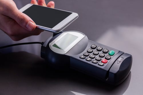 Man using smartphone to express pay against grey background