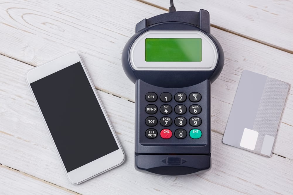 Overhead of pin terminal and smartphone on a wooden table
